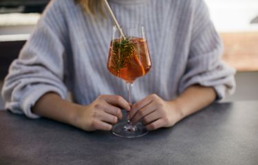 Frau hält ein Aperitif-Glas mit Rosmarinzweig im Hotel Bühelwirt, Ahrntal